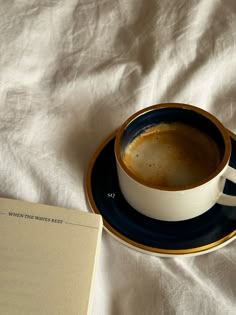 a cup of coffee sitting on top of a saucer next to an open book