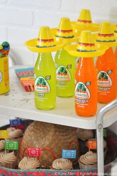 an assortment of orange juices and cupcakes on a table in front of a white brick wall