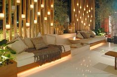 a living room filled with lots of furniture next to a wall covered in bamboo screens