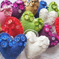 there are many different colored heart shaped brooches on the white table cloth with buttons