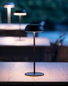 a table with two lamps on it and some chairs in the backgroung