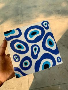 a hand holding up a piece of paper with blue and white designs on the outside