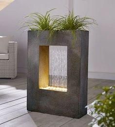 a planter with water flowing out of it on top of a wooden floor next to a couch