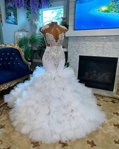 a white wedding dress on display in front of a fireplace