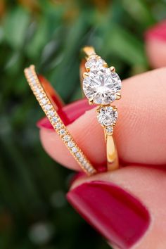 a woman's hand holding an engagement ring with two diamonds on top of it