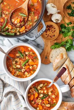 two bowls of vegetable soup with bread on the side