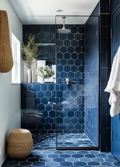 a bathroom with blue tile and hexagonal tiles on the floor, along with a shower