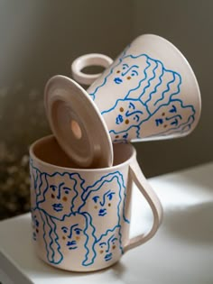 two cups with faces painted on them sitting on a table