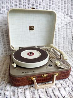 an old record player sitting on top of a suitcase