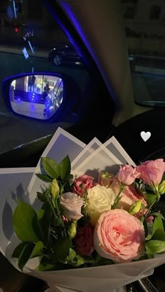 a bouquet of flowers sitting in the passenger seat of a car with blue lights behind it