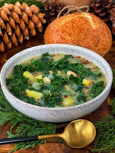 a white bowl filled with soup next to some pine cones and other food on a wooden table