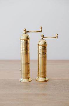 two golden salt and pepper shakers sitting on top of a wooden table