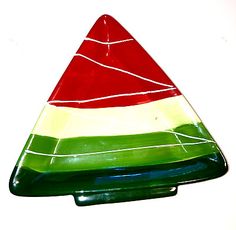 a red, white and green triangle shaped glass object on a white surface with lines running through it