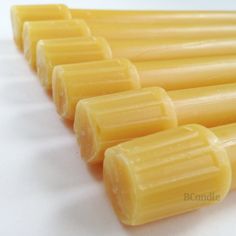 several yellow candles lined up on a white surface