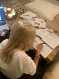 a woman sitting at a table with her laptop and papers in front of her on the floor