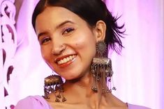 a woman wearing earrings and smiling at the camera