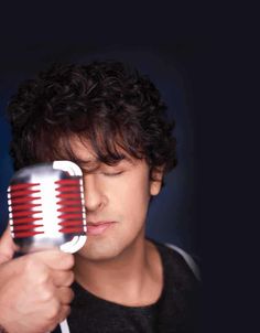 a man holding a red and white hair dryer in his right hand while looking at it