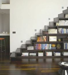 a living room filled with furniture and a book shelf next to a stair case full of books