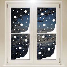 the window is decorated with snowflakes and trees in winter night time as seen from outside