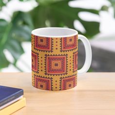 a coffee mug sitting on top of a wooden table next to a book and plant