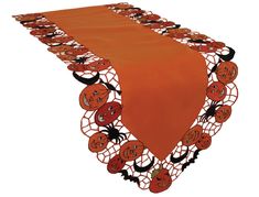 an orange table runner with pumpkins and spider web on the top, along with black cats