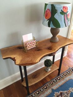 a wooden table with a lamp on top of it next to a rug and wall