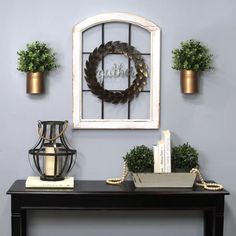 a table with some plants on top of it and a mirror hanging above the table