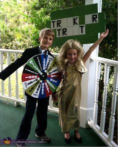 two people standing next to each other on a porch with a wheel of fortune sign