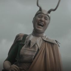 a statue of a man with horns on his head is laughing and holding something in his hand