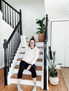 a woman is sitting on the stairs with her hand in the air and pointing up