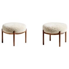 a pair of stools with sheepskin cushions on each side and wooden frame legs