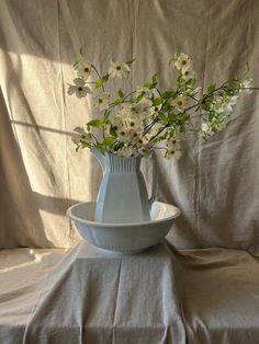 a vase with flowers in it sitting on a table cloth next to a white bowl