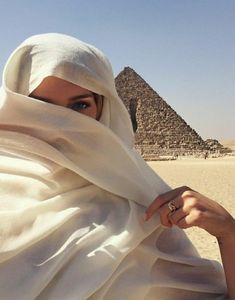 a woman wearing a headscarf in front of the pyramids