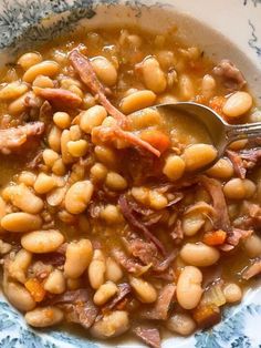 a bowl filled with beans and ham on top of a blue and white table cloth