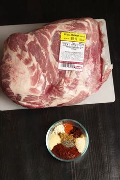 raw meat sitting on top of a cutting board next to a bowl of spices and seasoning