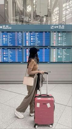 a woman is pulling her luggage through an airport terminal with lots of signs in the background