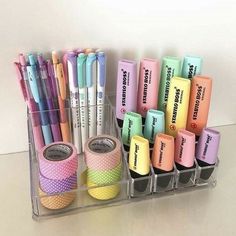 several different colored pens and pencils are in a holder on the table next to each other