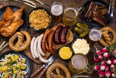 a table topped with lots of different types of food next to beer glasses and utensils