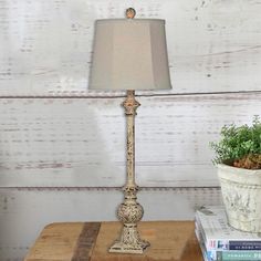 a lamp sitting on top of a wooden table next to a potted plant and books