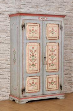 an old painted armoire in front of a brick wall