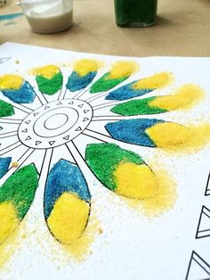 a drawing with yellow, blue and green colors on paper next to paintbrushes