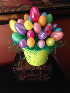 a yellow vase filled with lots of colorful eggs