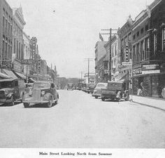 an old black and white photo of cars driving down the street