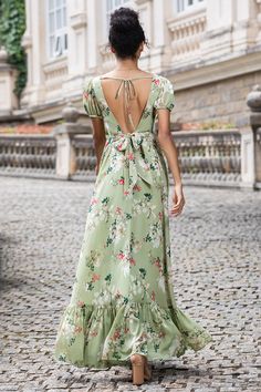 a woman in a long dress walking down a cobblestone street with her back to the camera