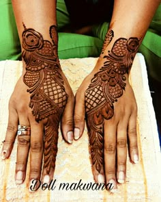 two hands with henna tattoos on them, one is holding the other hand and the other