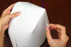 two hands are working on an origami box