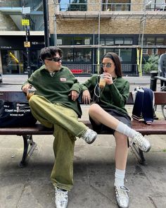 two people sitting on a bench drinking beverages