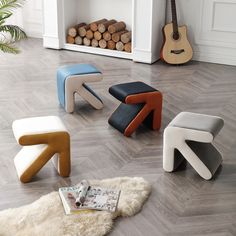 four different colored stools sitting on the floor in front of a fire place and fireplace