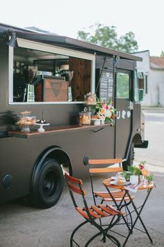 the food truck is parked on the side of the road with tables and chairs around it