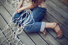 a woman sitting on top of a wooden floor next to a pile of white cords